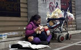 Homeless woman fee3ding baby on the sidewalk.