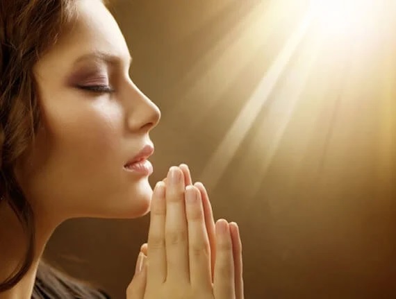 A person praying with her hands together

Description automatically generated
